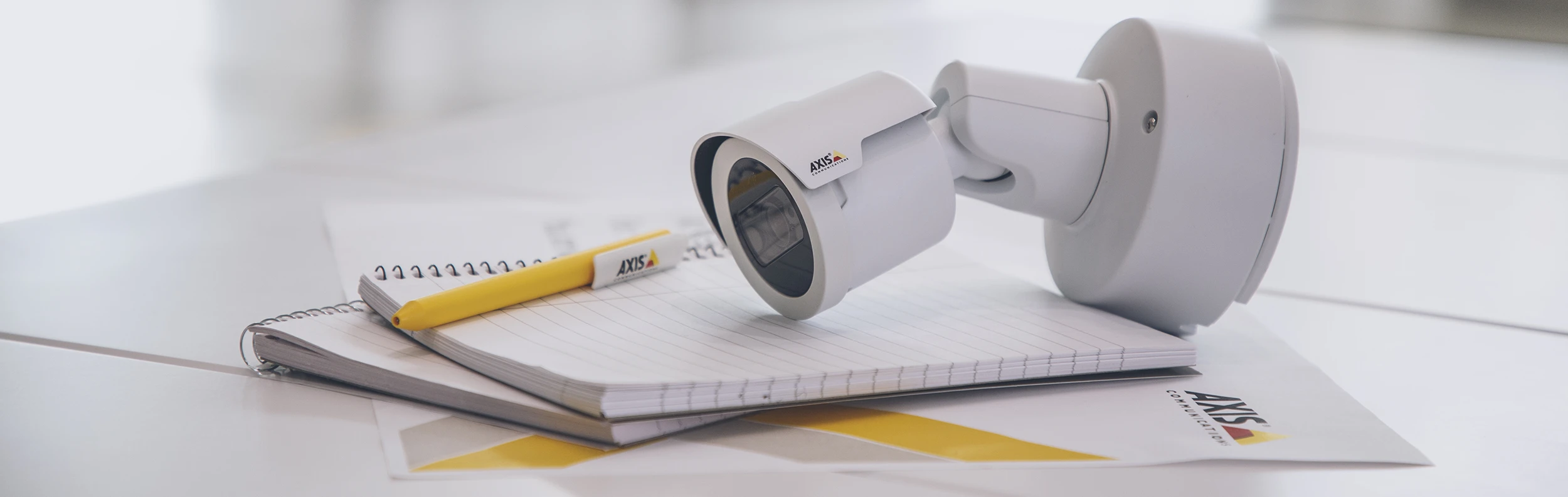AXIS CCTV video camera on a desk with pen and paper.