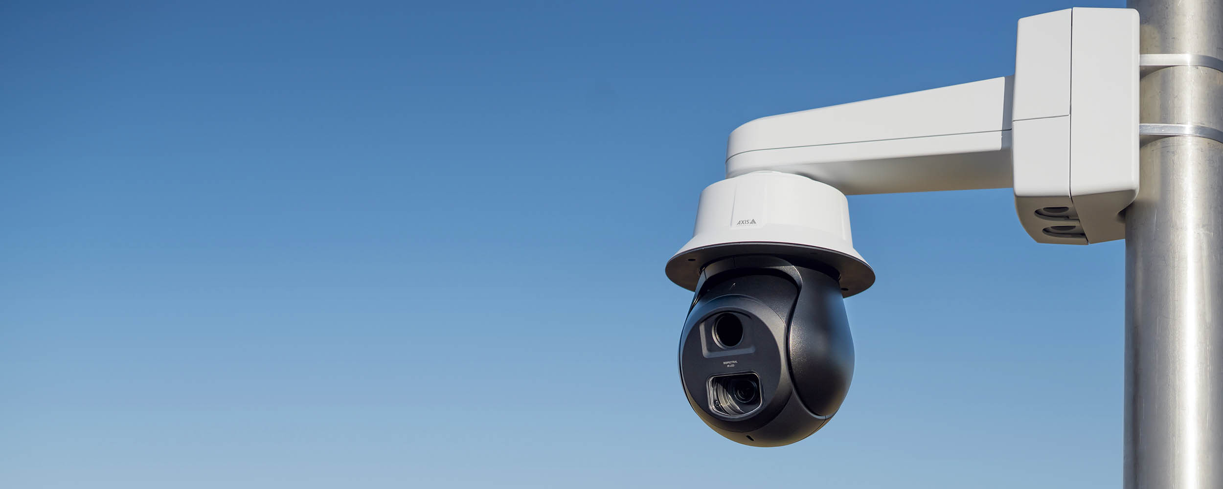 AXIS Q6411-LE Bispectral Video Camera mounted on a pole outdoors during the daylight hours.
